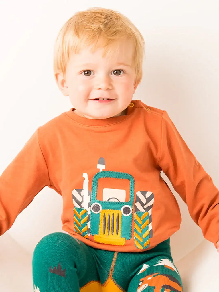 Blade & Rose Rustic Farmyard Top. Child wearing an orange shirt with a tractor design on a white background