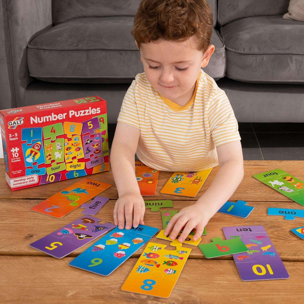 Galt Number Puzzles. Child playing with number puzzles on a wooden table, with a Galt Number Puzzles box in the background.