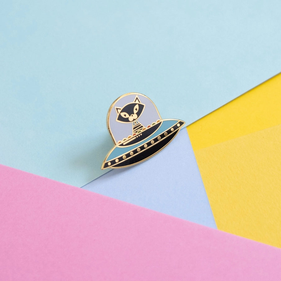 Munchquin Atomic Space Kitten Hard Enamel Pin - a quirky and fun enamel pin badge featuring a quirky black cat flying on a spaceship!