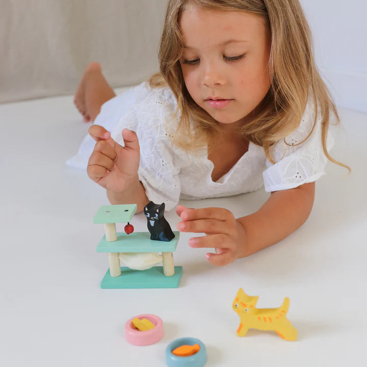 Tender Leaf Pet Cats Set Child playing with a small toy cat tree and figurines on a light surface.