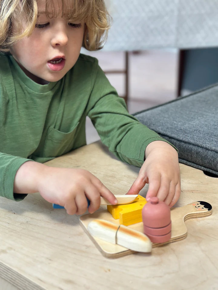 Mentari Smiley Charcuterie Chopping Board. Child playing with wooden toy food items on a table