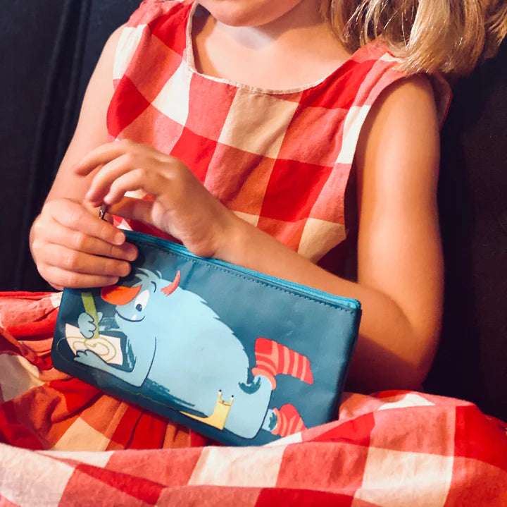 Scruffles Monster Print Pencil Case by ThreadBear Design. Child holding a blue pouch with a cartoon design, wearing a red and white checkered dress.