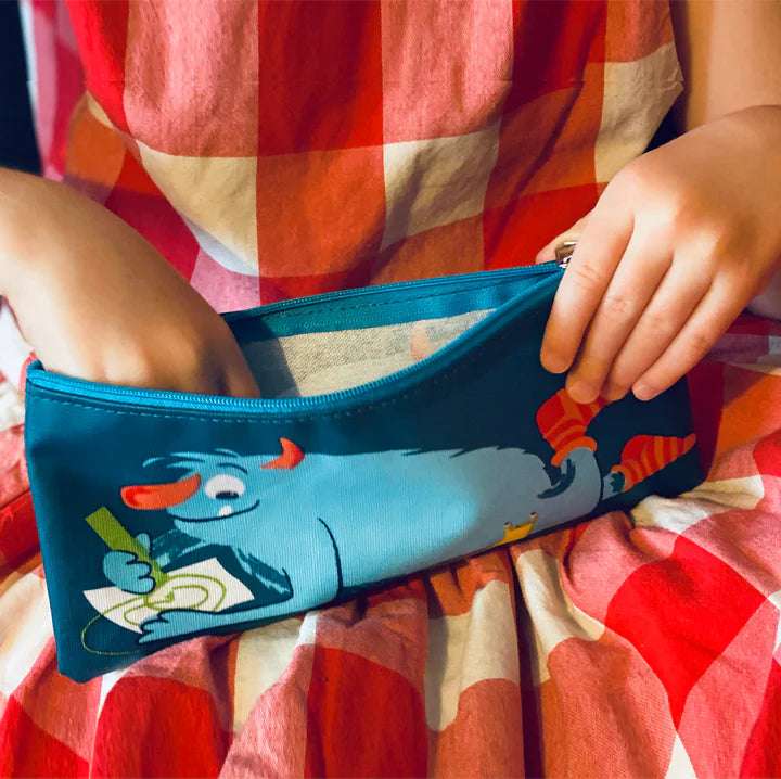 Scruffles Monster Print Pencil Case by ThreadBear Design. Person holding a blue pouch with a cartoon character on a red and orange checkered fabric background