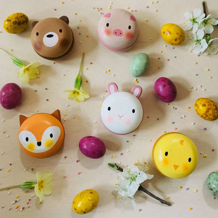 Animal Macarons Wooden Toy Set by Tender Leaf Toys – Cute & Colorful Play Food! . Colorful animal-shaped candies on a wooden surface with flowers and Easter eggs.