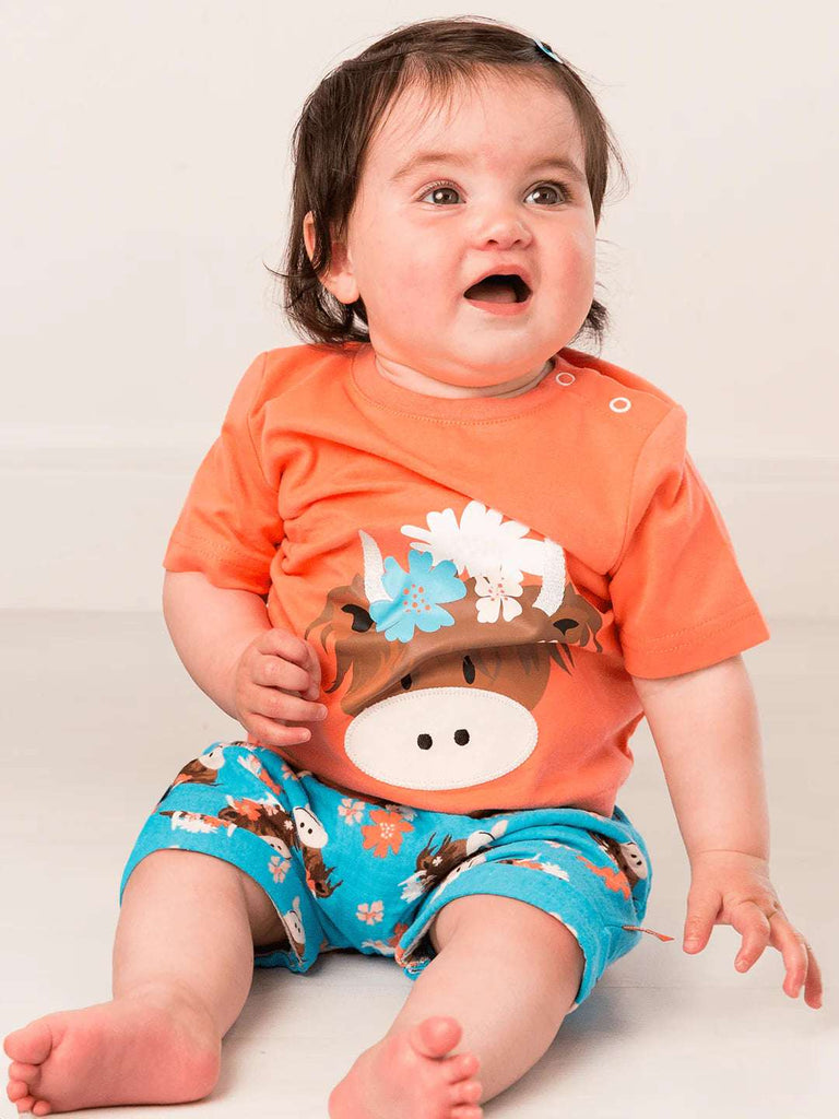 This gorgeous bright orange short-sleeved t-shirt features a cheeky Highland Coo Bonnie face with pretty floral detail, perfect for summer