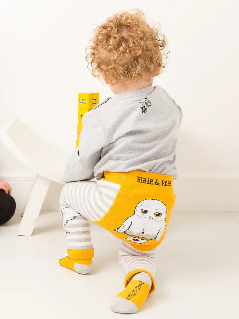 Blade & Rose Harry Potter Hedwig Owl Leggings. Child wearing a gray shirt and yellow apron with owl design, sitting on a white surface.