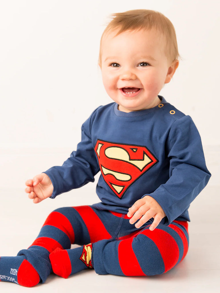 Blade & Rose Superman Leggings. Baby wearing a Superman outfit with a blue shirt and red and blue striped pants on a white background