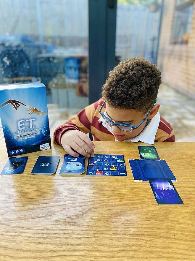 Child playing with E.T. themed card game at a table. E.T The Extra Terrestrial Card Game