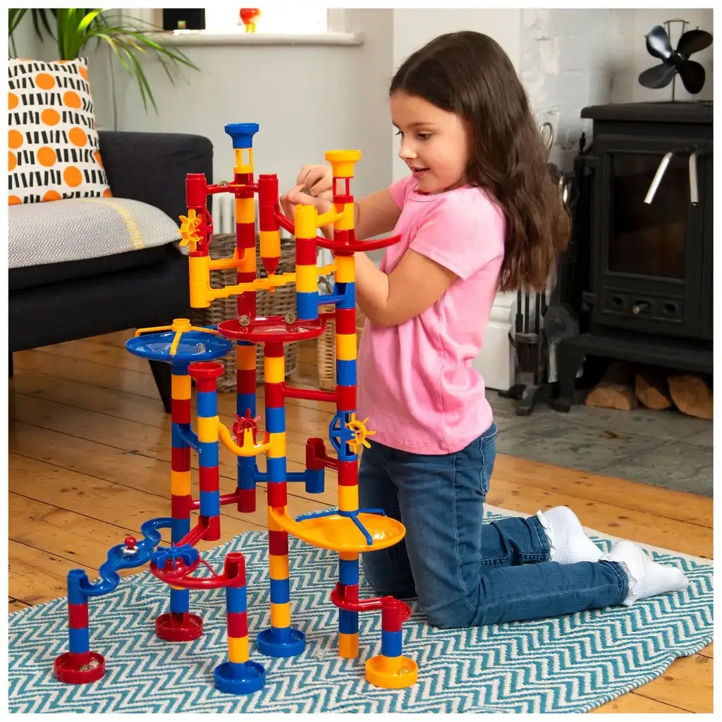 Galt Mega Marble Run. Child playing with a colorful marble run toy set in a living room.