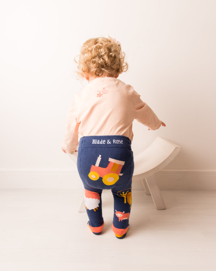 Blade & Rose Meadow Farmyard Leggings. Child wearing navy leggings with a tractor design and 'Blade & Rose' branding, standing on a white floor.