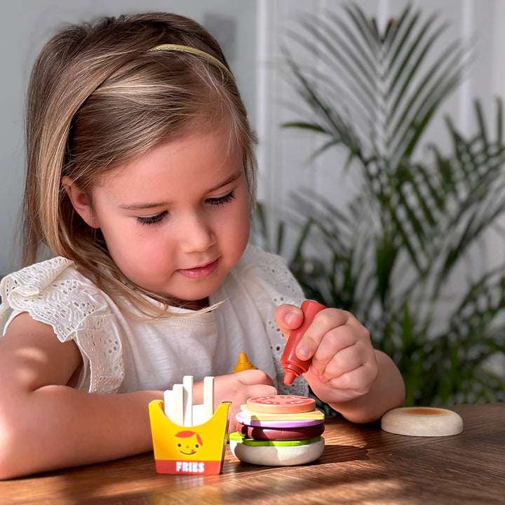 Mentari Mentari Take-out Burger Set. Young girl playing with a toy hamburger set on a wooden table.
