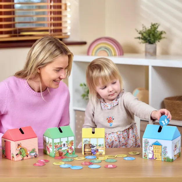 Orchard Toys Peter Rabbit Posting Game. Woman and child playing with colorful house-shaped boxes on a table.