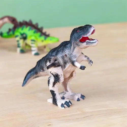 Rex London Wind-Up Dinosaur Toy - T-Rex. Toy dinosaur figure on a wooden surface with a green background