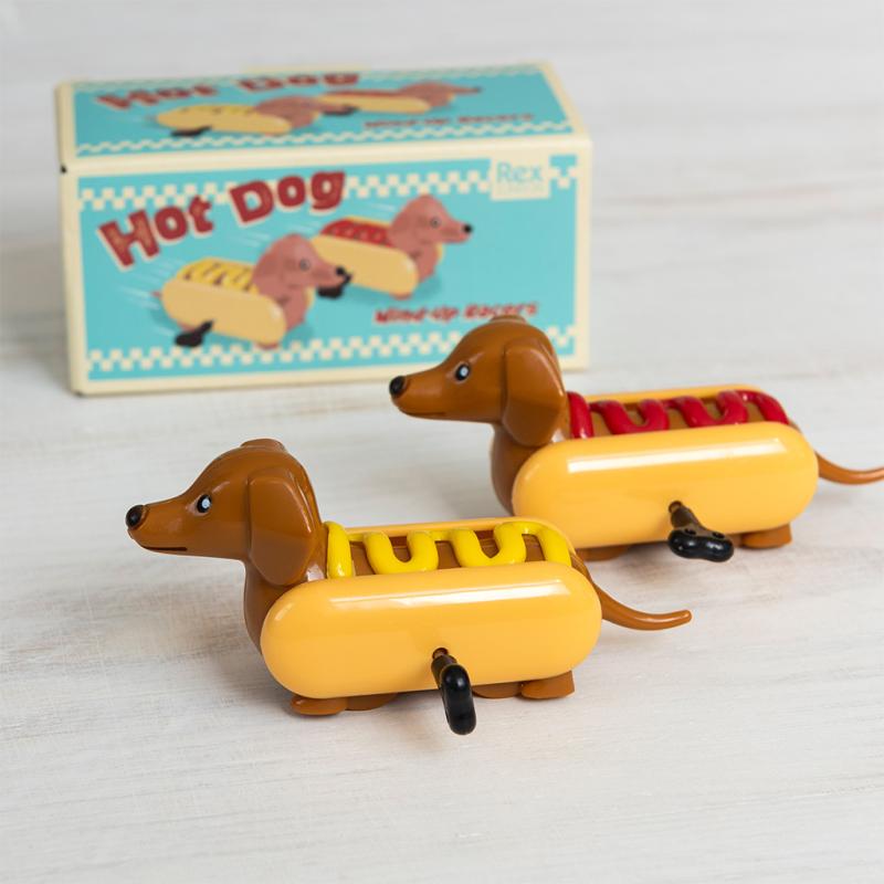 Rex London Hot Dog Wind-up Racers (Set of 2). Two toy hot dogs with a box labeled 'Hot Dog' in the background.
