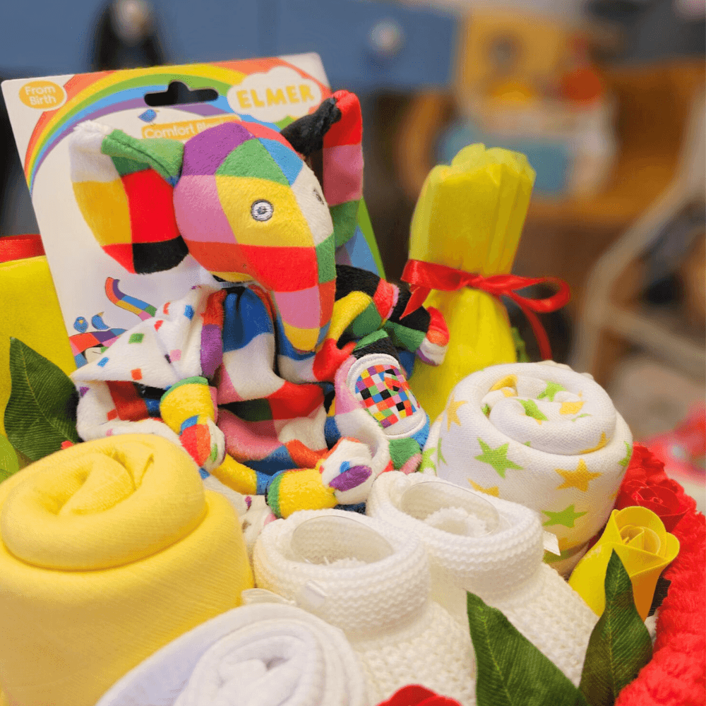 Bright nappy cake. Created using nappies and a soft baby blanket (and filled with lots of goodies), the gorgeous cake is then hand-wrapped in cello
