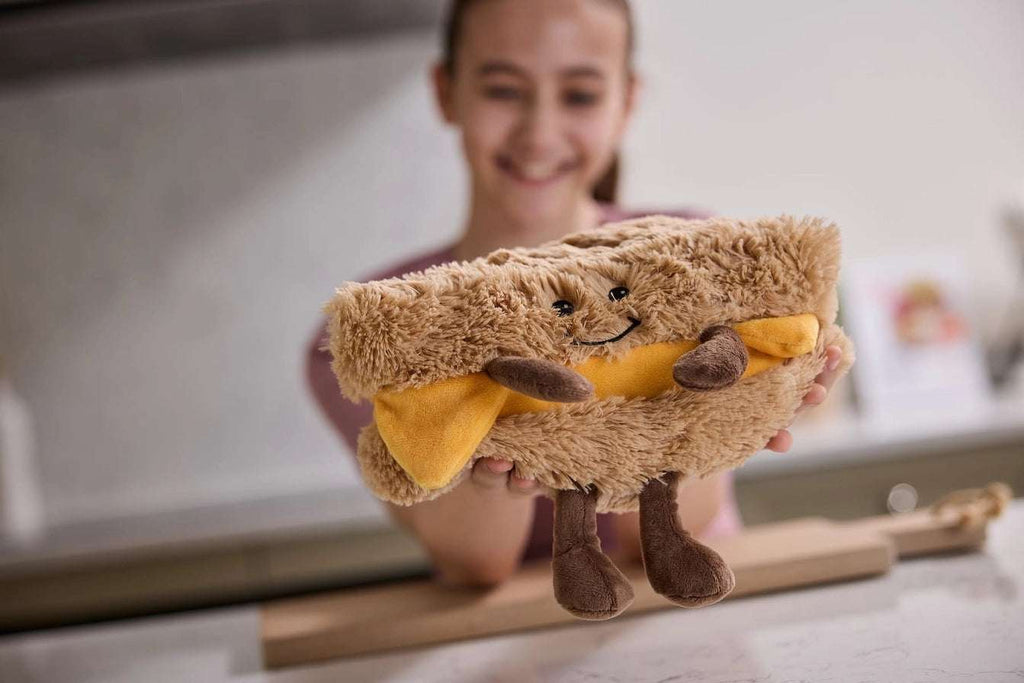 Child holding a plush toy shaped a sandwich. Warmies Grilled Cheese - 