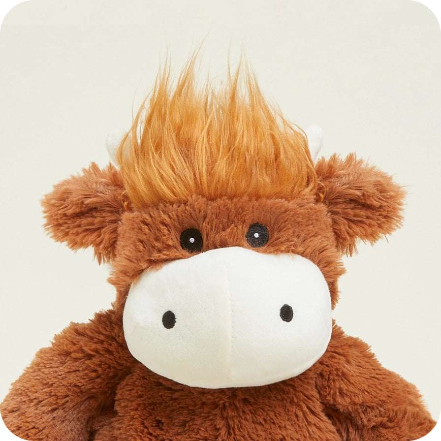 Warmies Highland Cow - Brown plush highland cow toy with a white muzzle on a light beige background