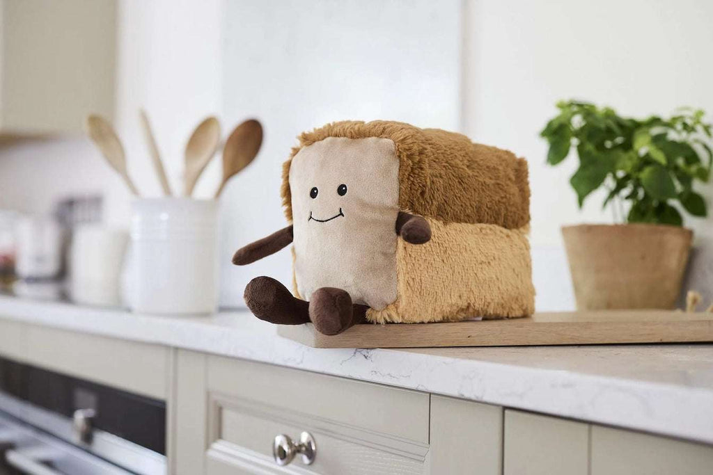 Warmies Loaf of Bread - Plush toy loaf with a smiling face on a kitchen counter
