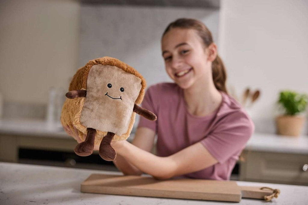 Warmies Loaf of Bread - Plush toy loaf with a smiling face - being held in a kitchen