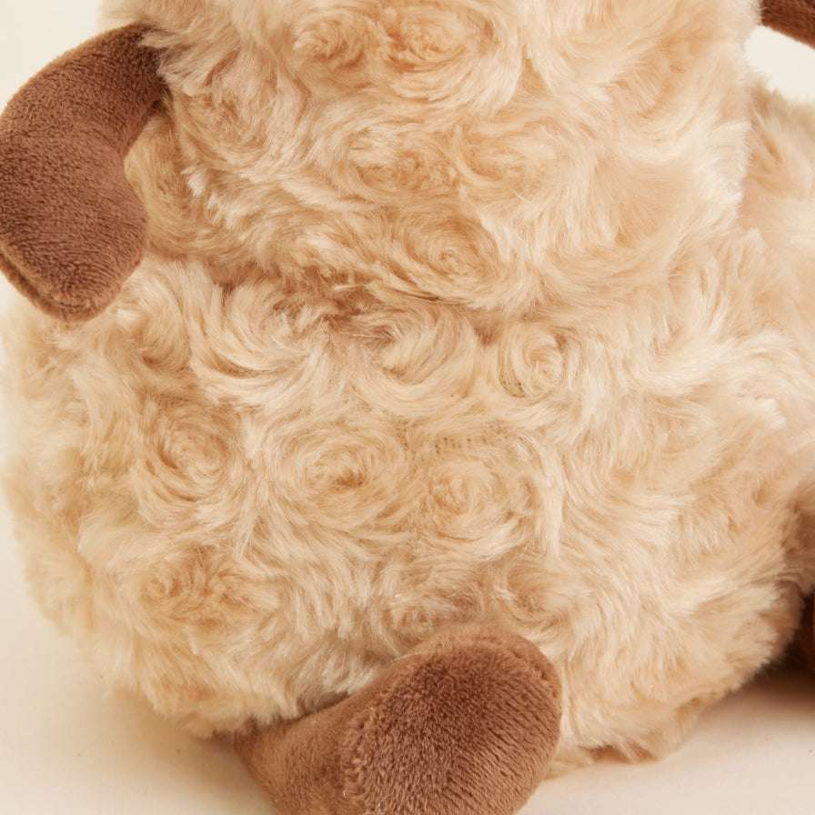 Warmies Peanut - Plush toy peanut with brown feet and arms on a beige background - closeup of fur