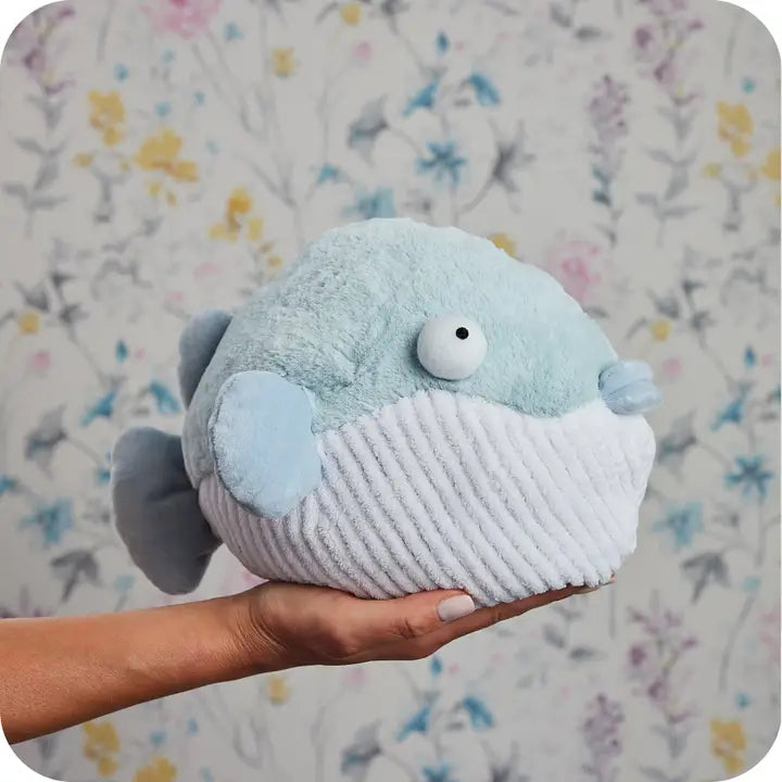 Warmies Pufferfish Plush toy fish held by a hand against a floral background