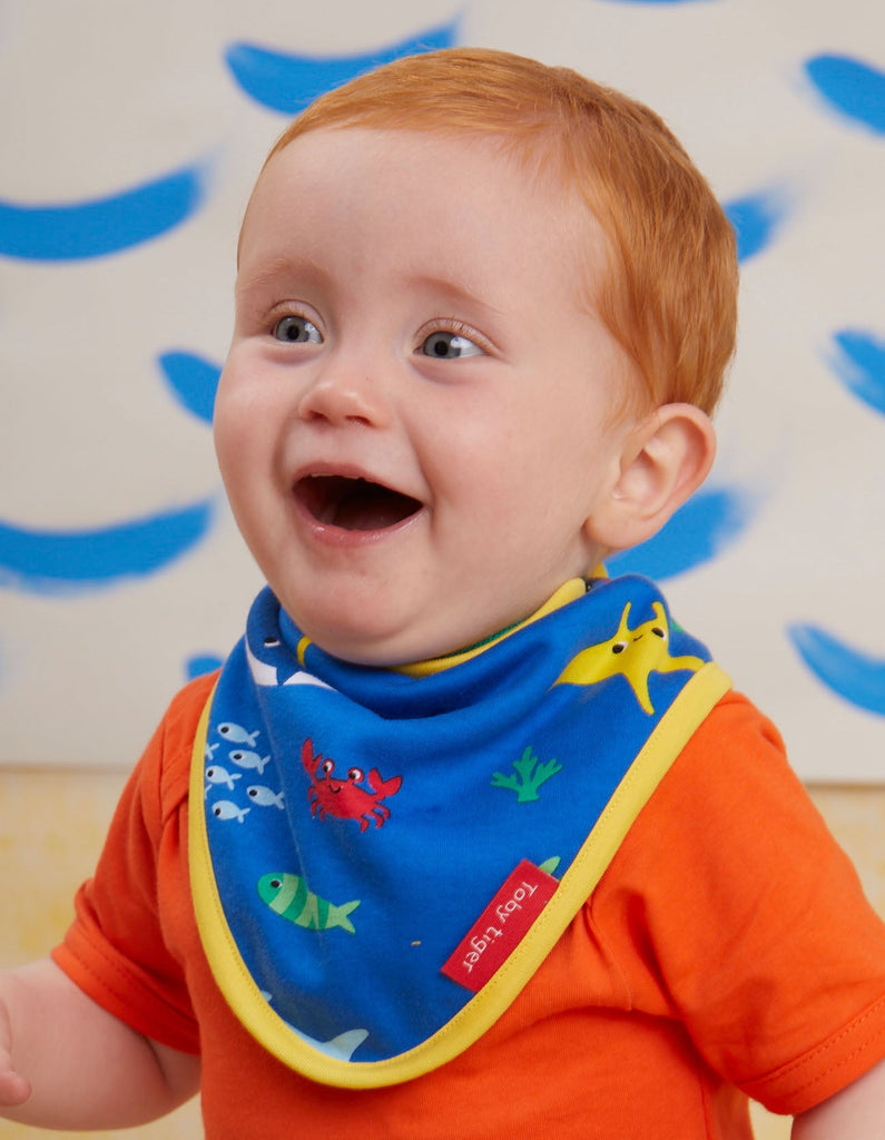 Toby Tiger Sealife Dribble Bib- A gorgeous bib in blue featuring cute underwater creatures with a bold yellow trim. Sold by Say It Baby Gifts