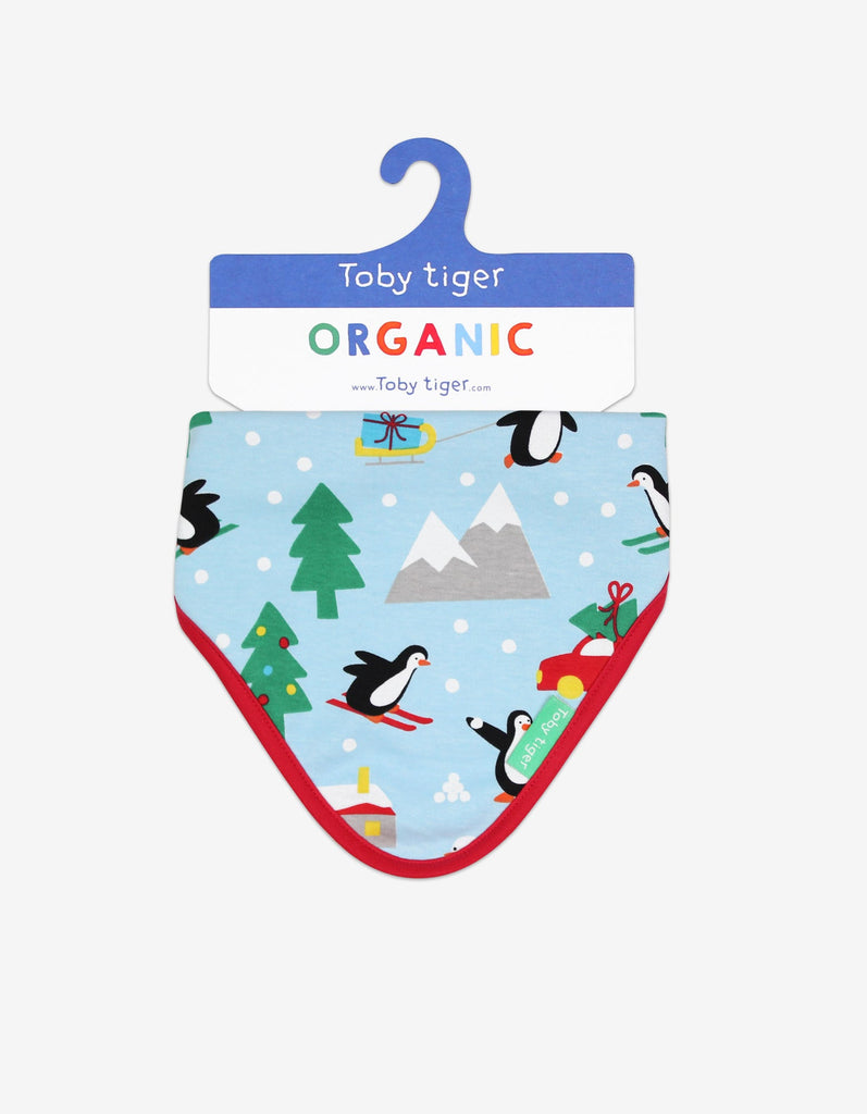 Toby Tiger Penguin Christmas Dribble Bib - A gorgeous bib in pale blue featuring sledging penguins and a sweet winter scene with a bold red trim. Sold by Say It Baby Gifts